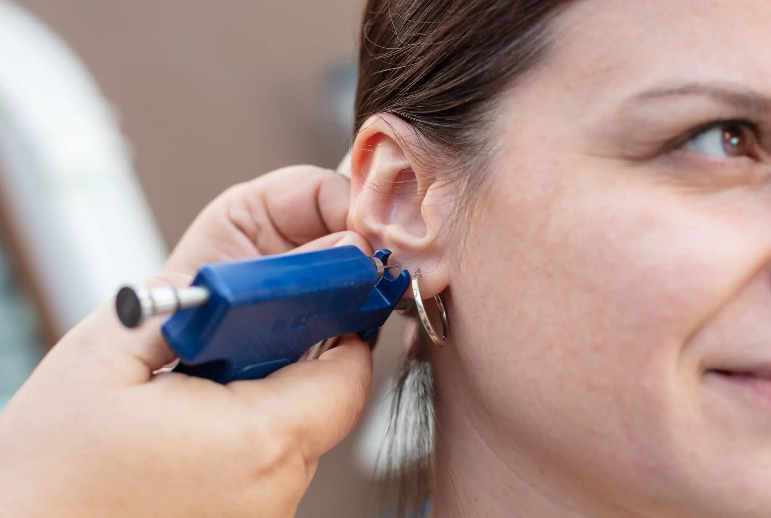 Woman having ear piercing process